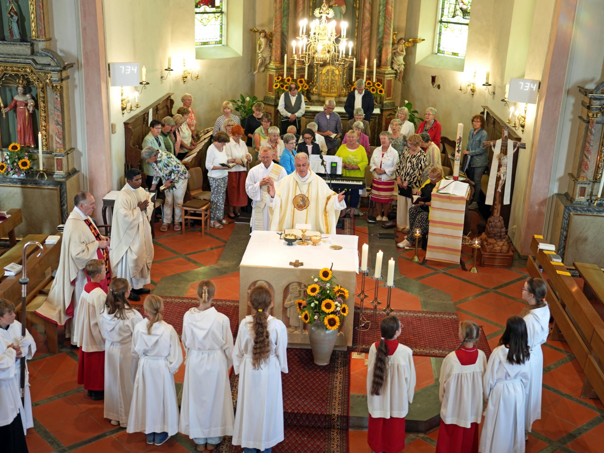 Weihbischof Peters, ein Chor sowie Messdienerinnen und Messdiener feiern Gottesdienst in der Kirche in Faid.