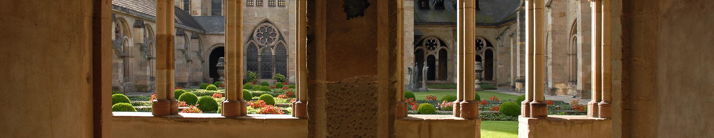 Blick durch zwei Torbögen in den Kreuzgang des Trierer Doms und in den Garten.