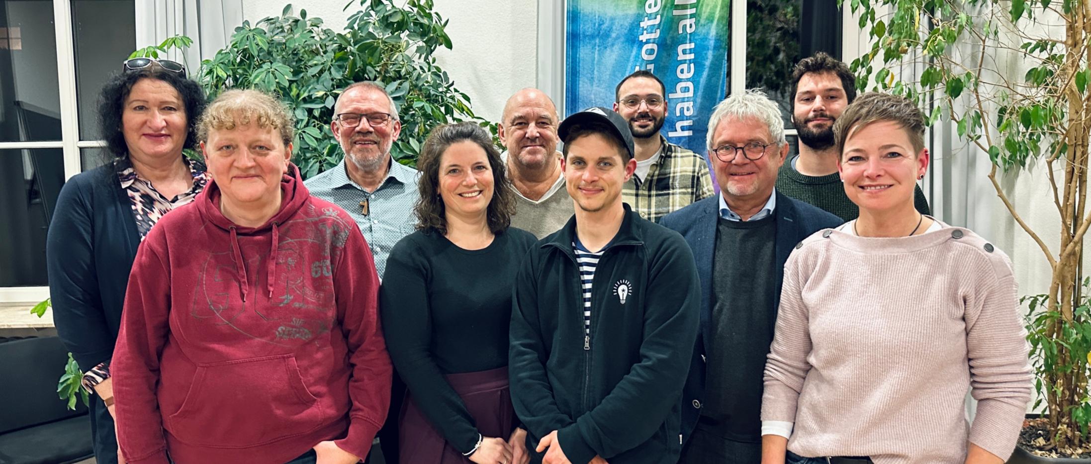 Gruppe steht lächelnd in einem Konferenzraum.