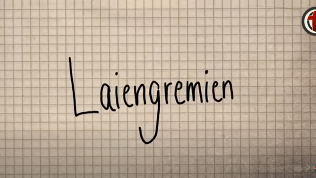 Screenshot aus dem Video. Zu sehen ist ein Papier mit dem handgeschriebenen Wort 'Laiengremien'